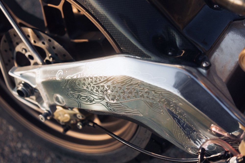 close view of ornate engraving on the curved swingarm