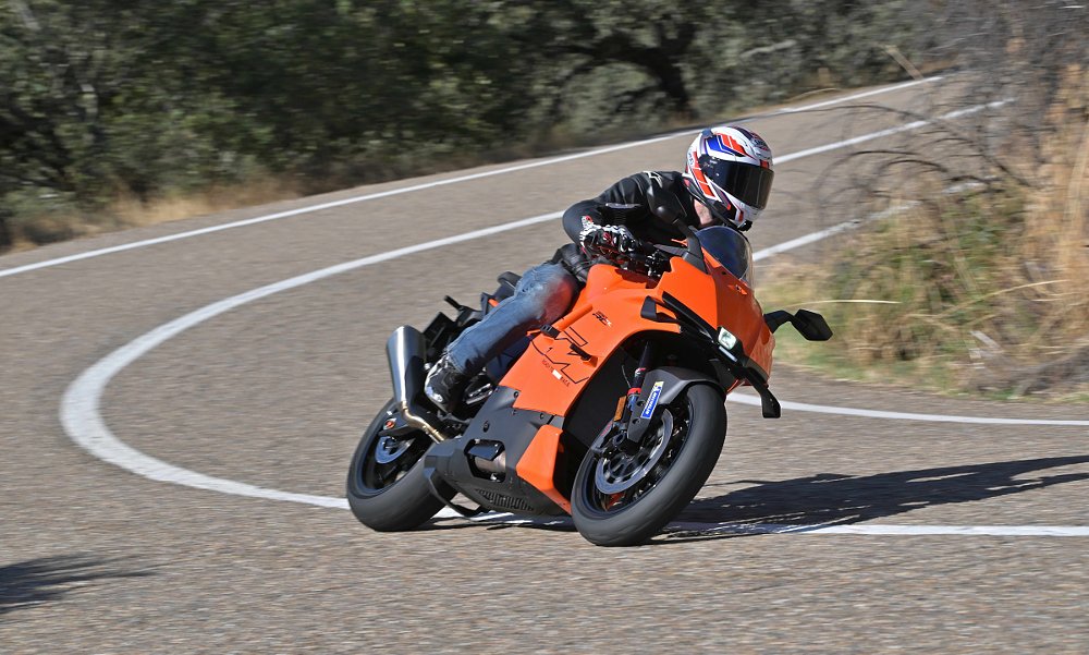 Zack riding the orange KTM RC R on a curving country road in Spain