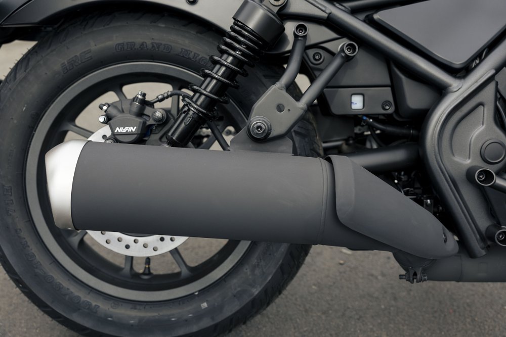 close view of rear shocks, exhaust, rear wheel