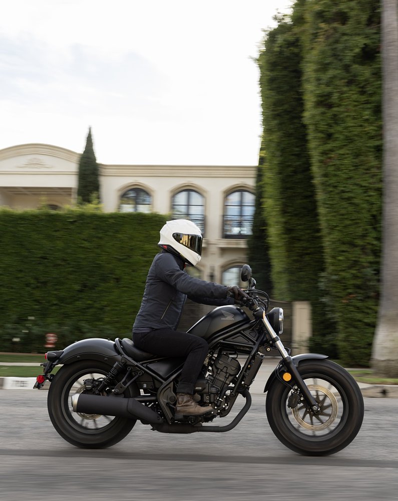 riding the Rebel 300 past a large mansion