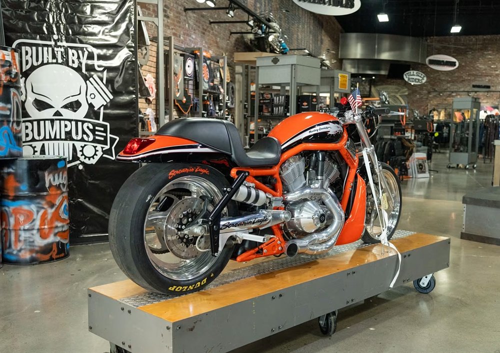 orange and black Harley-Davidson drag racing bike on a pedestal in a dealership