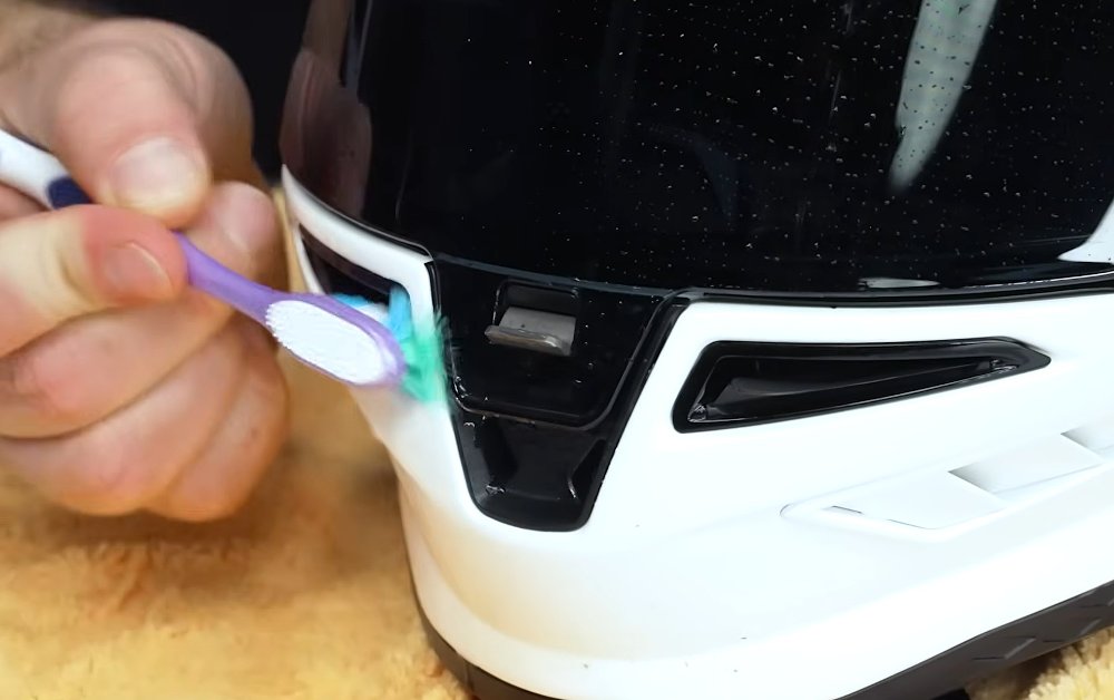 close view of a toothbrush reaching into a helmet vent to clean it
