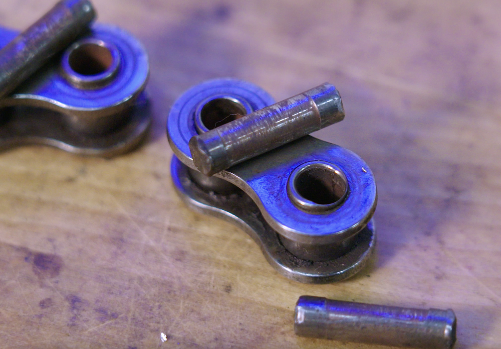 Motorcycle chain disassembled showing excessive pin and bushing wear