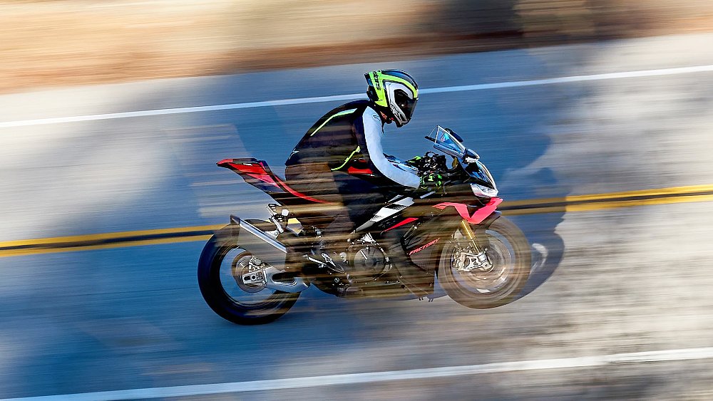 A sport bike rider flashes past the camera on a canyon road.