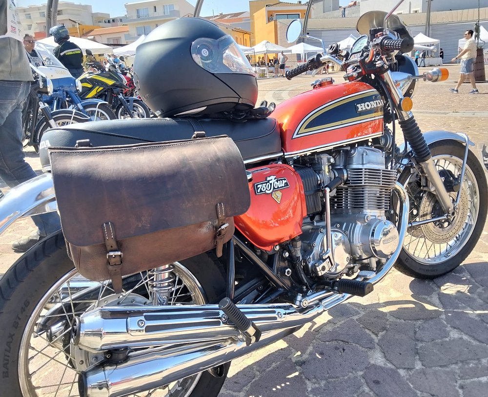 a 1975 orange Honda CB750 with leather saddlebags draped across the seat