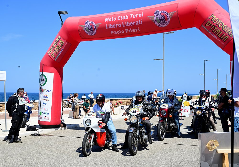 riders lined up to start the day's ride under a large red inflatable arch