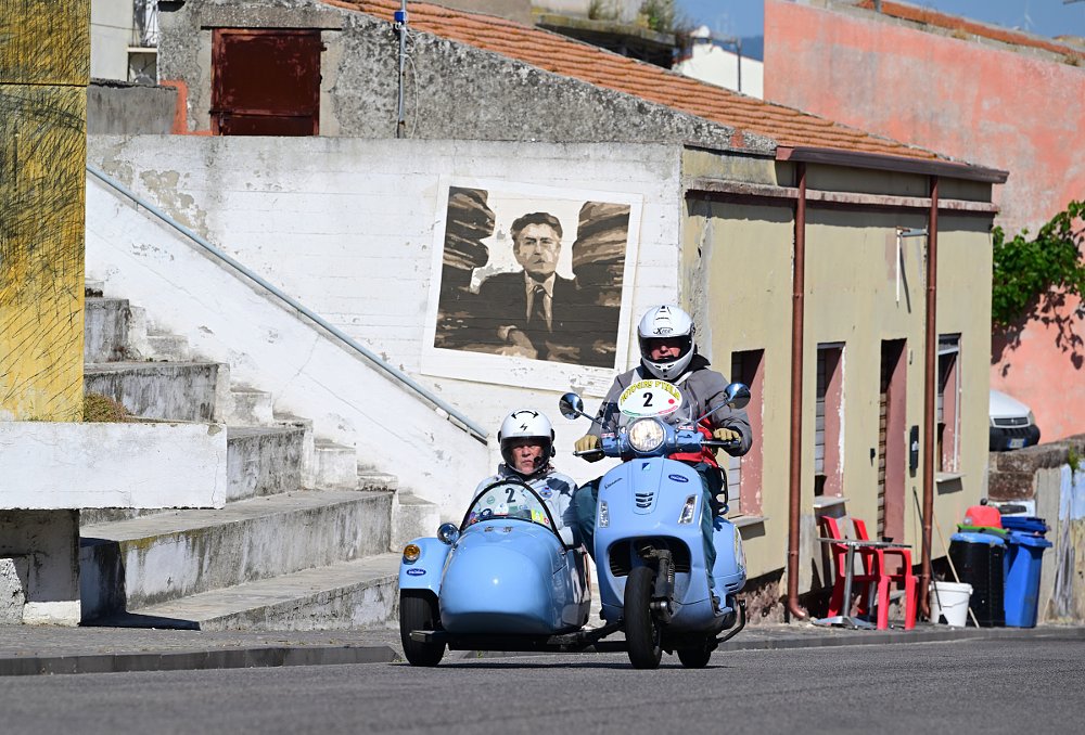 powder blue Vespa scooter and sidecar riding through an old village in Sardinia