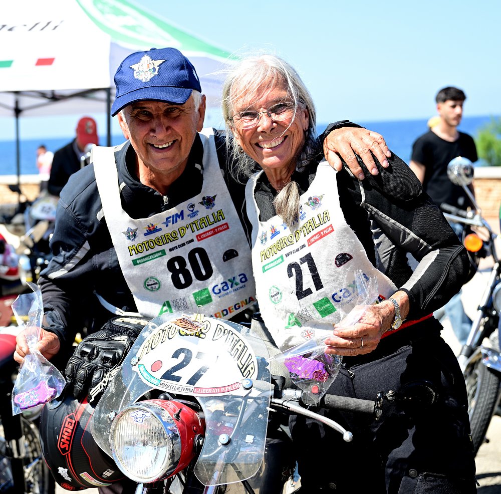 Robin, smiling, posing with another rider in their vintage-style riding gear