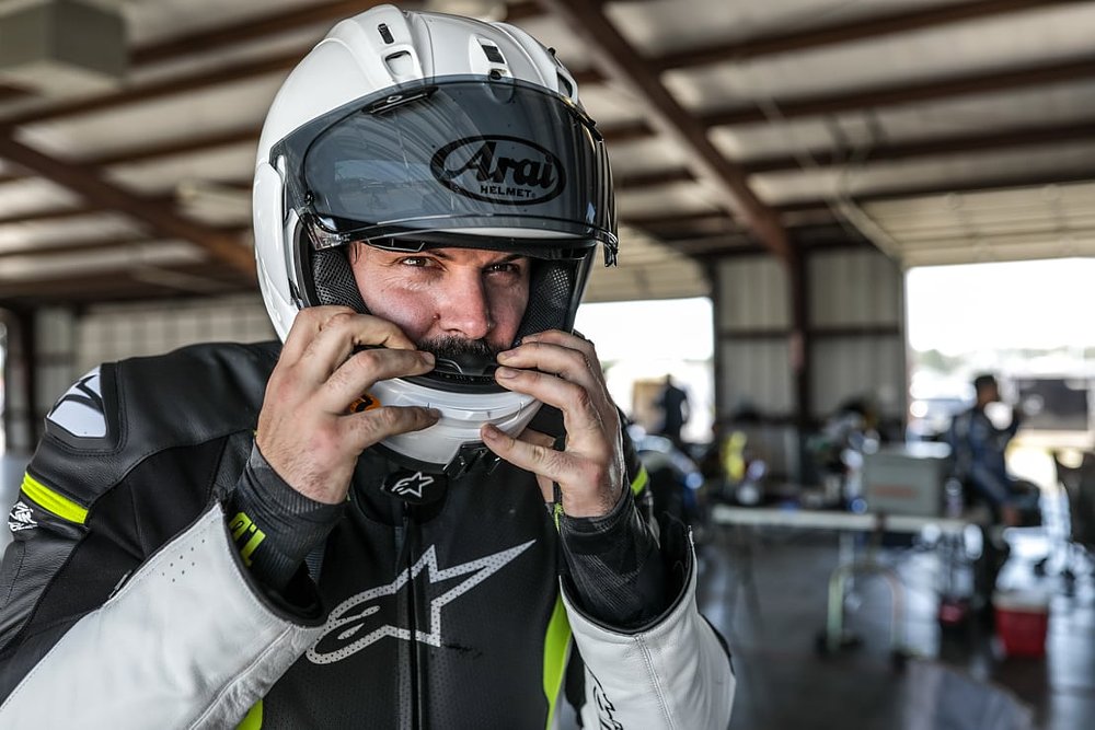 Spurgeon in leathers with a Klim base layer showing from the sleeve ends, ready to go onto the track with helmet on