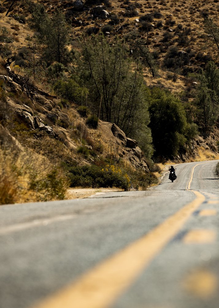 distant view of a motorcycle on a road through dry mountains
