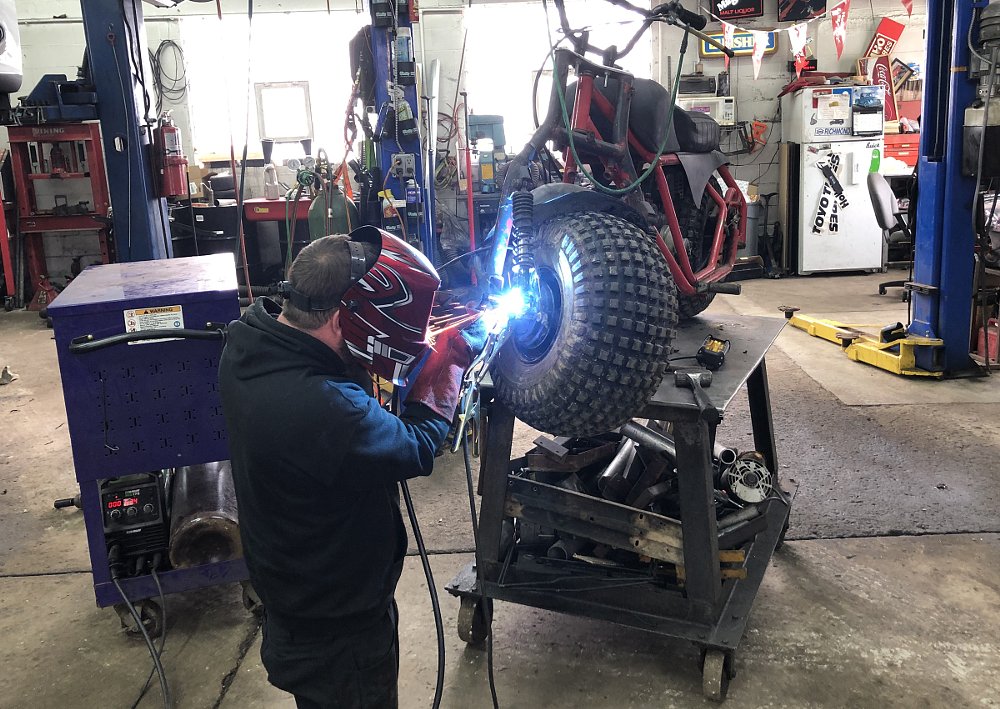 Ben welding on the front suspension of the minibike in the shop
