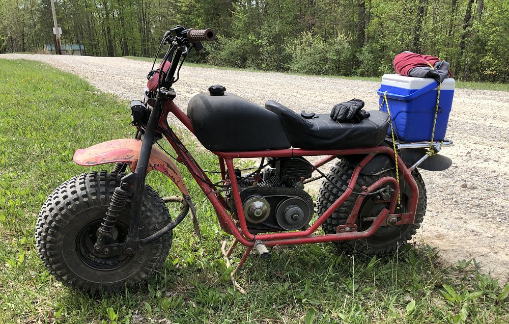 homebuilt minibike sitting by a dirt road