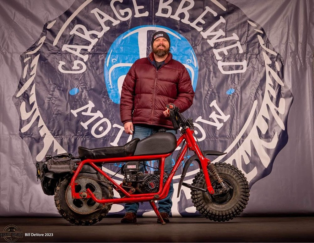 posing with the minibike in front of the Garage Brewed Moto Show banner