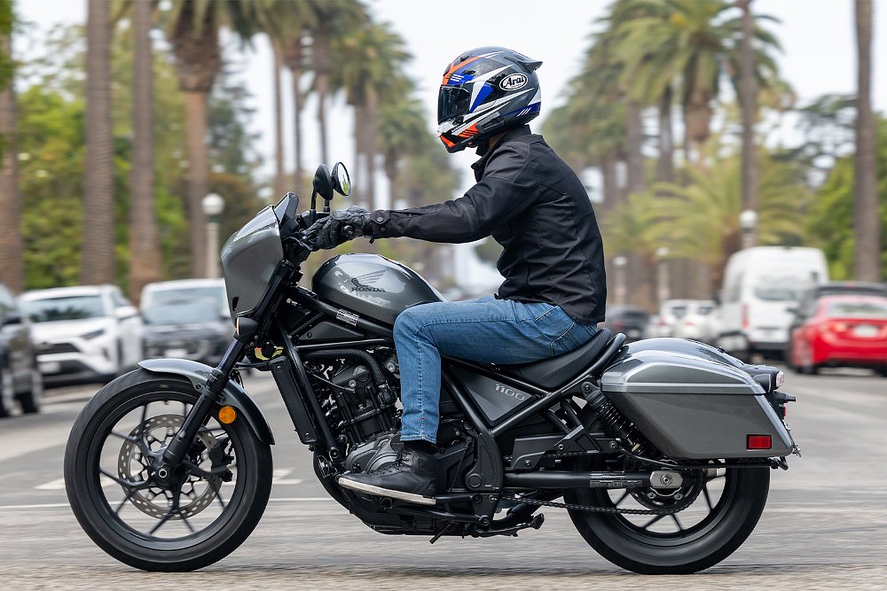 Dustin rides the Rebel 1100T past a palm tree-lined street.