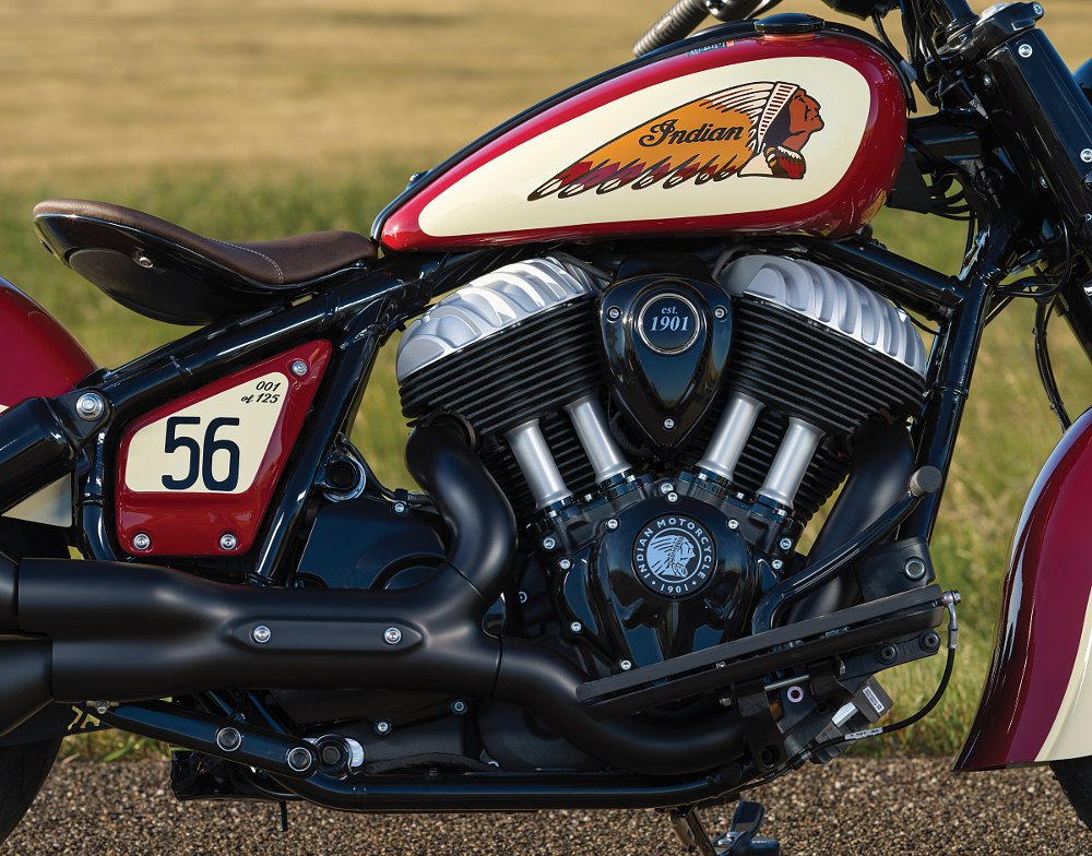 close view of the vintage-styled engine, multicolor logo on the red and cream tank, and the numbering that said '1 of 125' on the side plate along with a larger '56' like a race number
