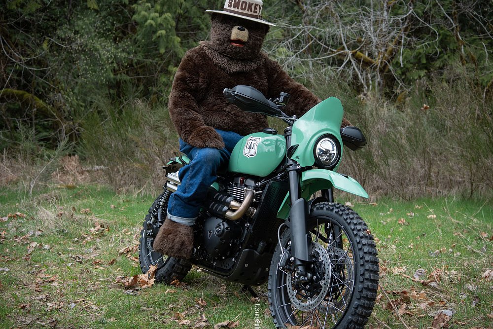 person in a Smokey the Bear costume sitting on the green Scrambler