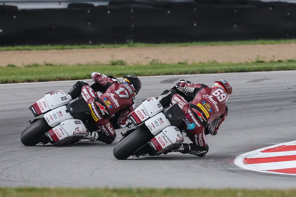 Herfoss and Gillim seen from behind, racing closely, leaned over in a corner on their Indian Challenger KotB race bikes