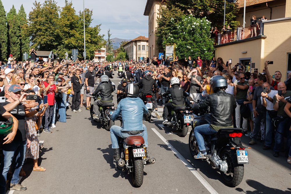 crowds line a street welcoming riders