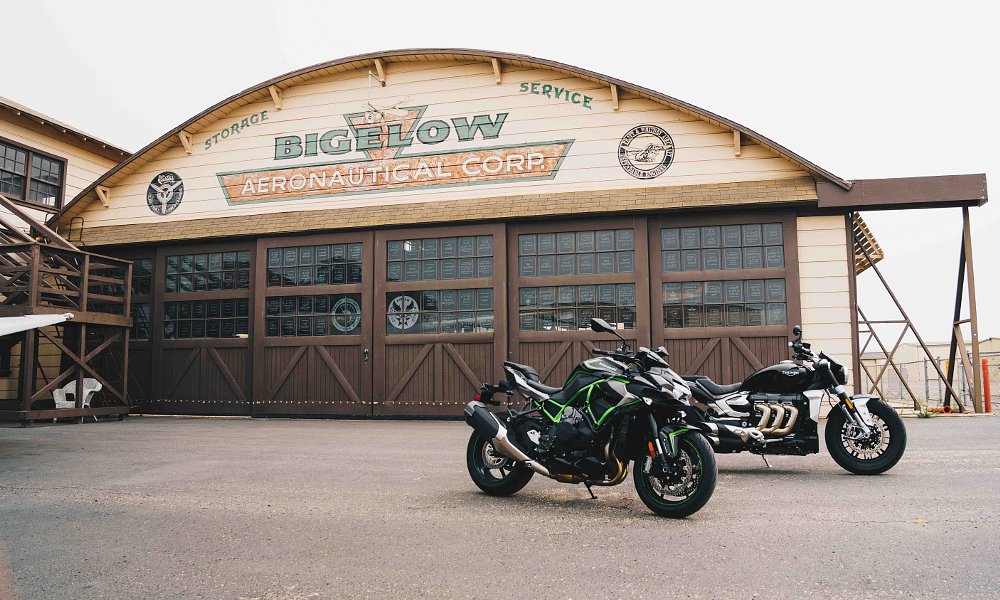Kawasaki Z H2 and Triumph Rocket 3 in front of airport hangar