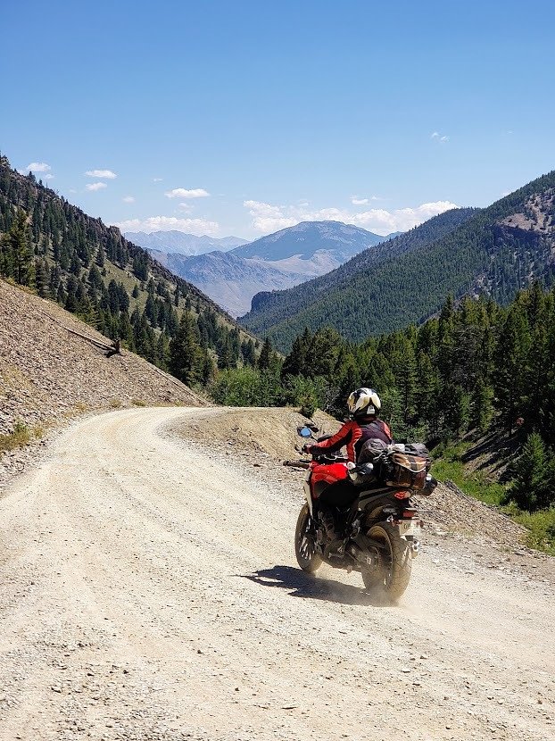 A photo of female rider Amanda riding on a gravel road on her Honda adv bike