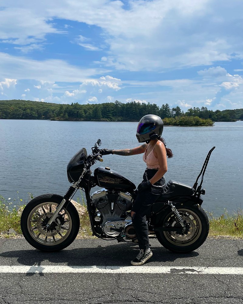 A photo fo female rider Sophia sitting on her Harley cruiser with helmet on