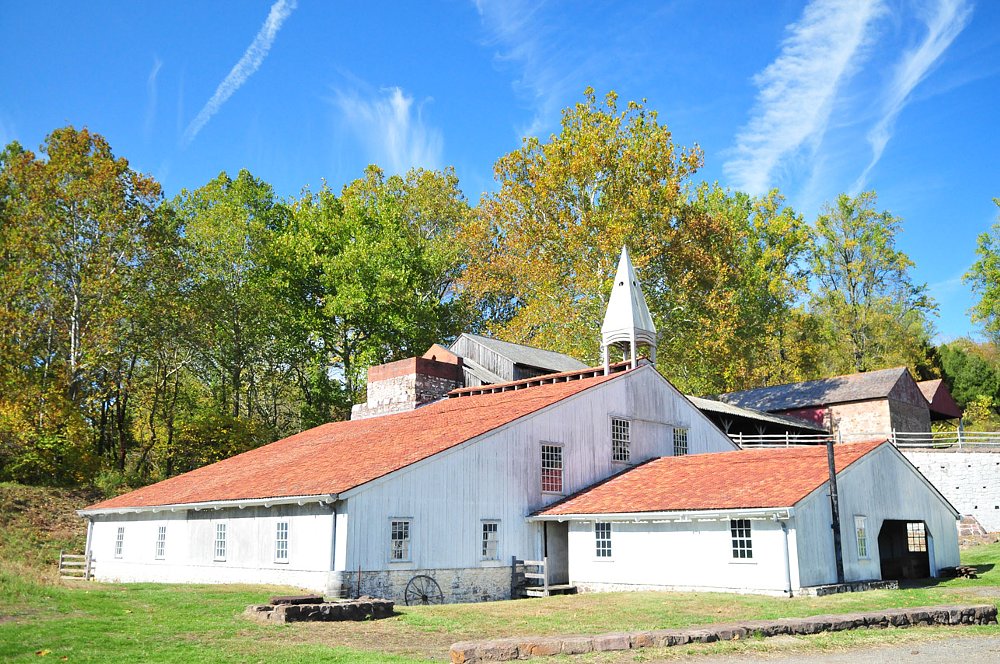 The Hopewell furnace has white paint finish and red roofing, it is a big building to house the forge