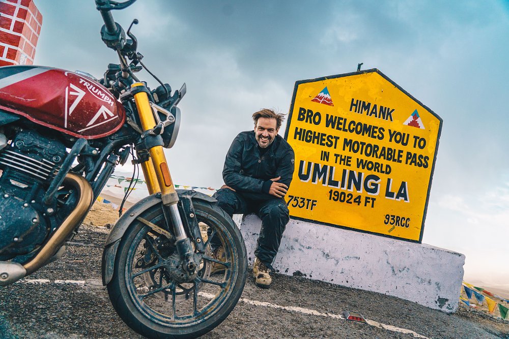 Spurgeon smiling in front of the Umlingla sign marking the highest road in the world