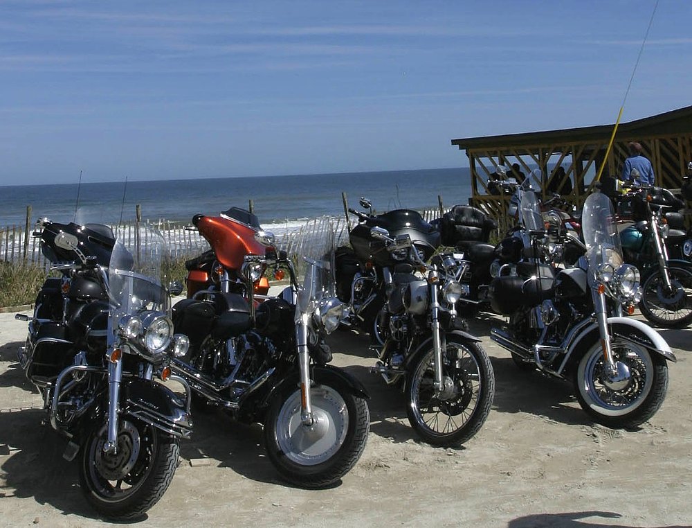a row of motorcycles parked by a snack shack on the beach