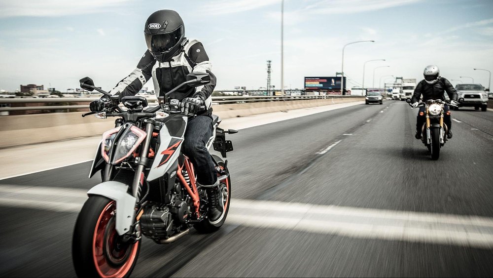 A photo of two motorcycle riders on the freeway in fast lane
