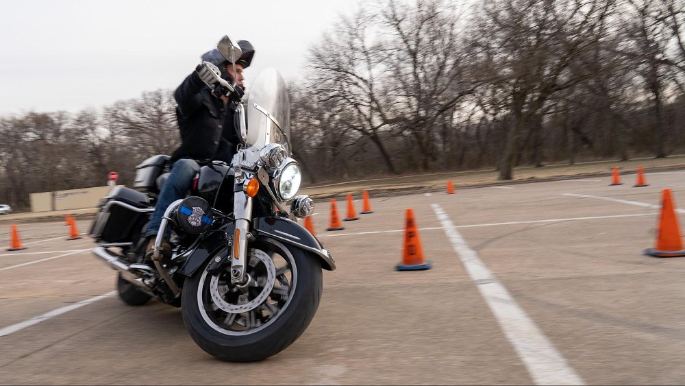 A motorcyclist rides a harley through a cone course in a parking lot