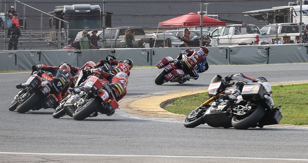 pack of KOTB motorcycles banked deeply into a curve