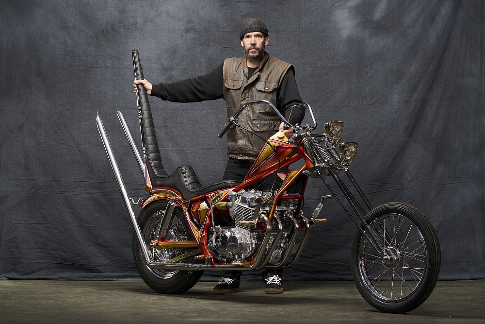 Craig Baum posing with his CB750 chopper for a studio photo