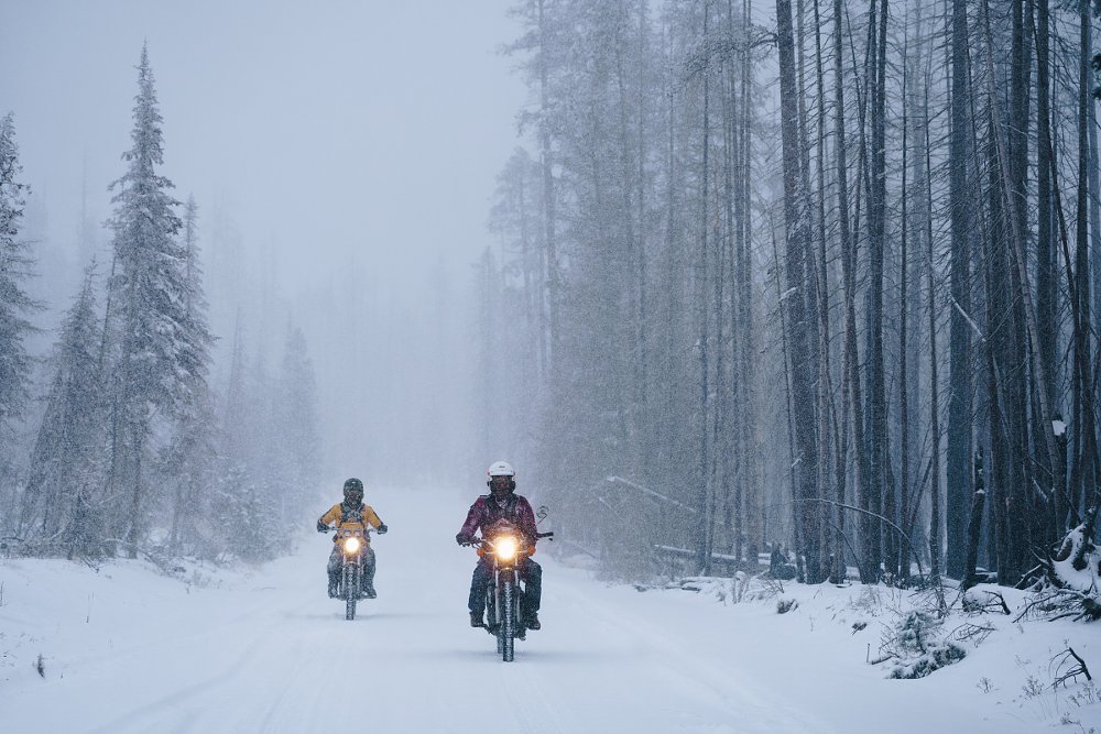 two motorcyclists riding through a snowstorm