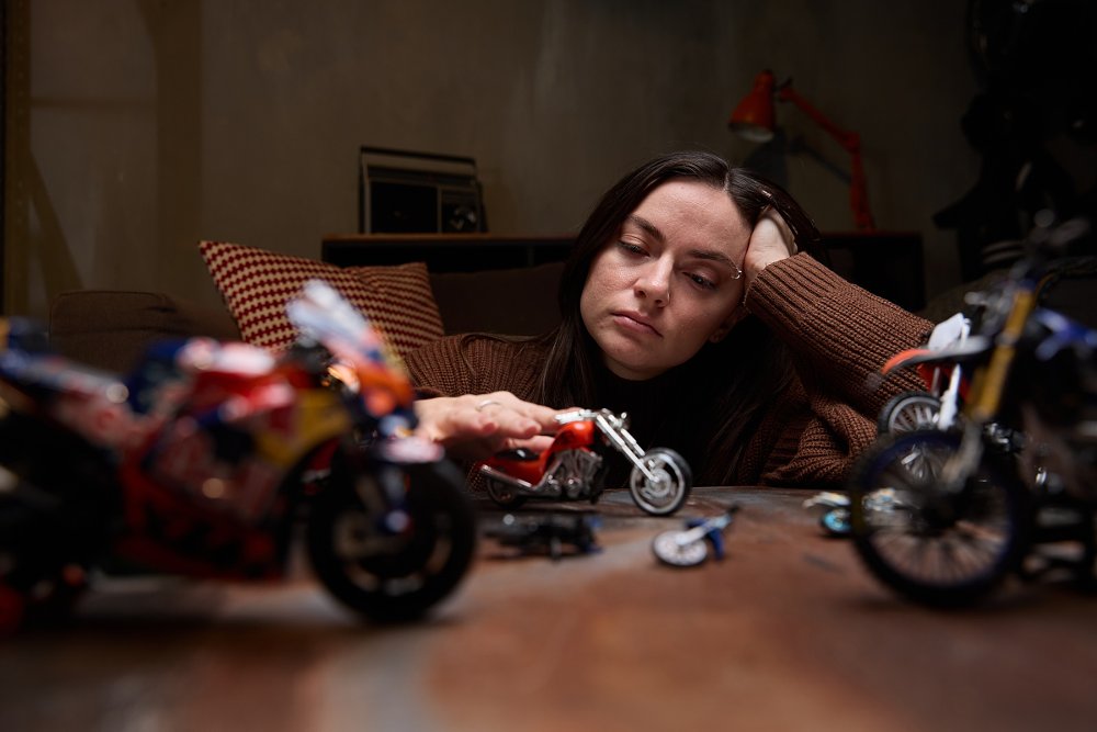 contemplative woman playing with toy motorcycles