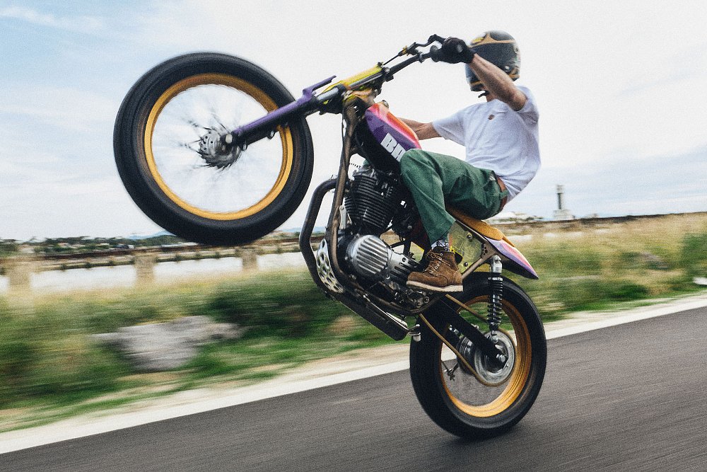 rider doing a wheelie on the custom SR400