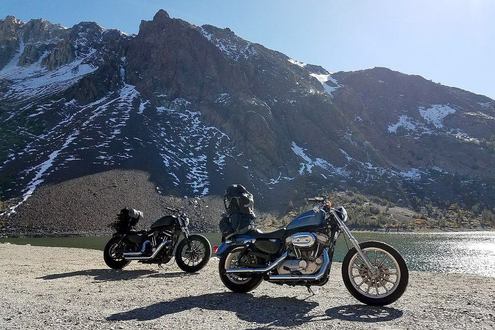 Two fully-packed Harley-Davidson Sportsters parked in front of a snow-covered mountain.