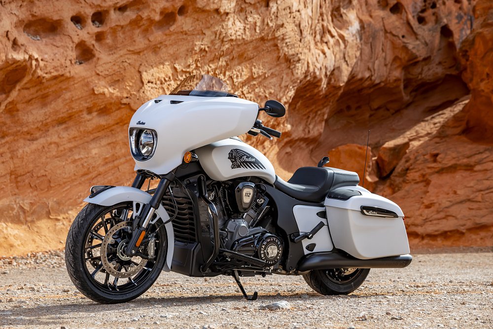 white Chieftain parked in front of red rock cliff