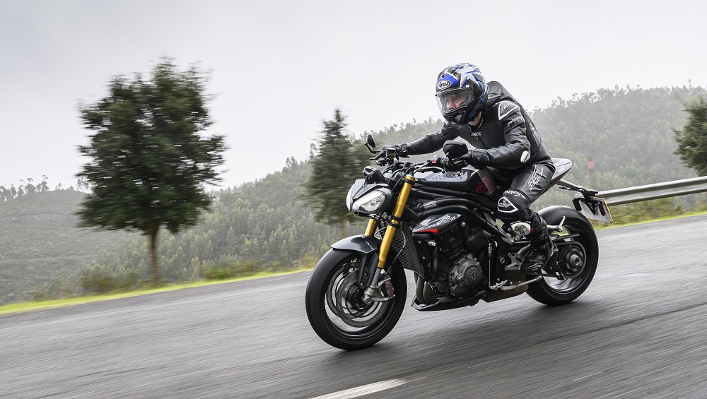 riding the Speed Triple RS on a wet road with fog in the background