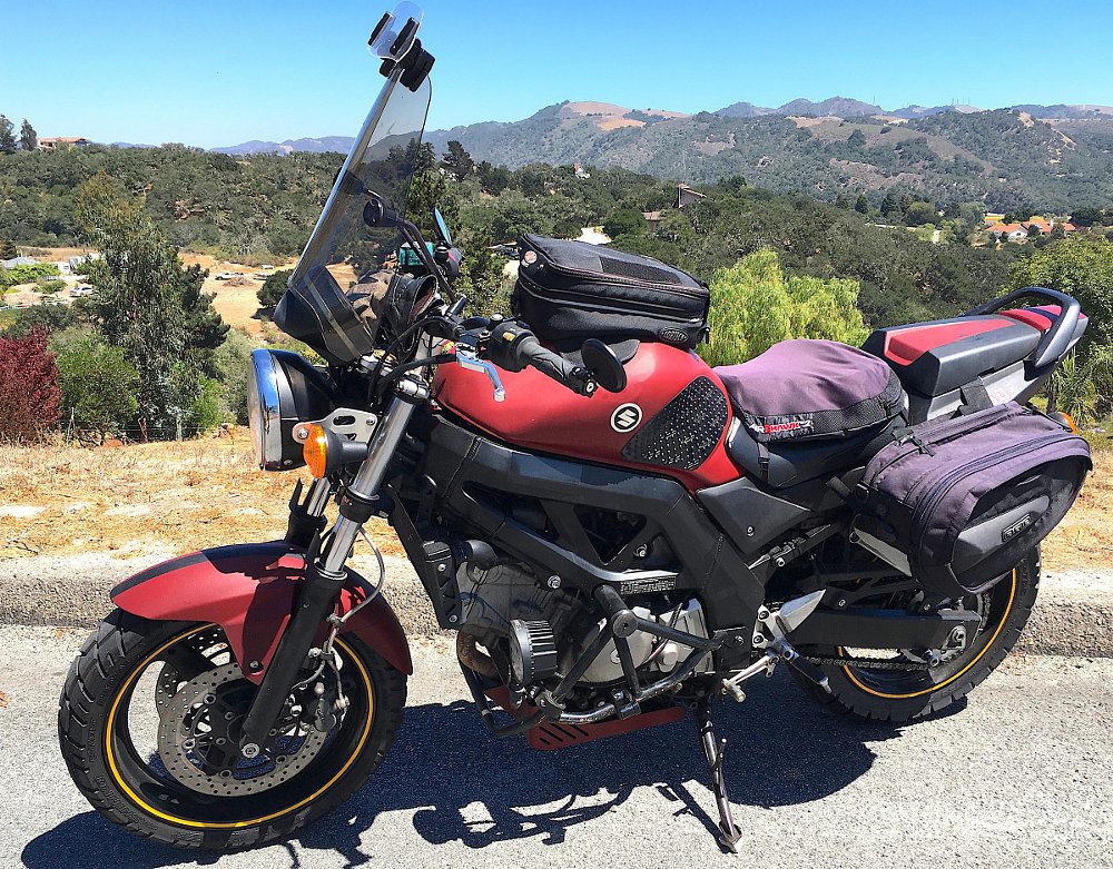 red Suzuki SV650 outfitted with a windshield, saddlebags and a tank bag for travel