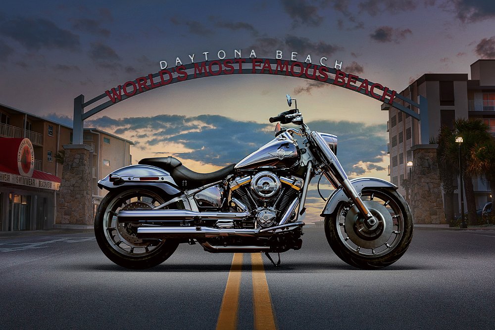 A side profile view of the 2025 Harley-Davidson Fat Boy Gray Ghost against the Daytona Beach strip.