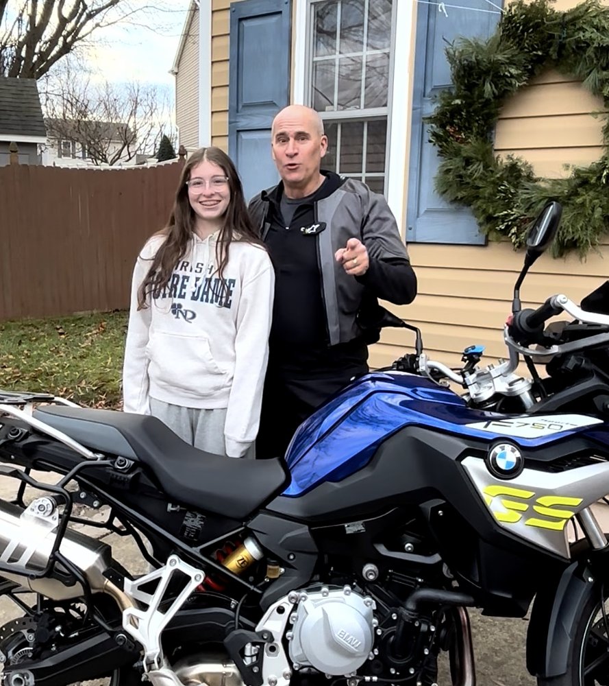 author posing with his teenage daughter and his blue BMW motorcycle