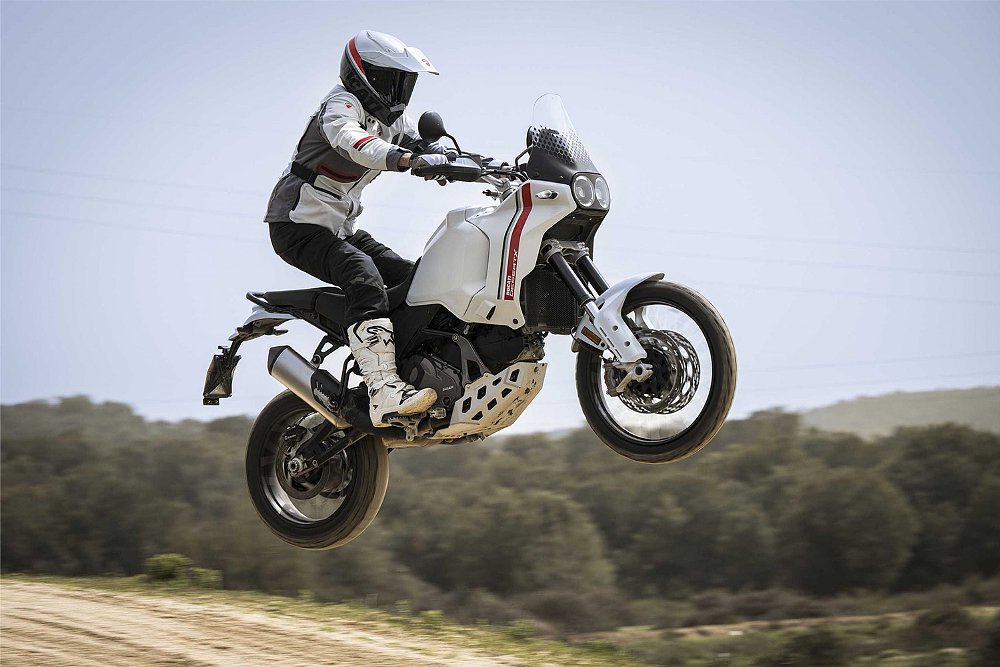 An off-road rider launches the Ducati DesertX off a jump.