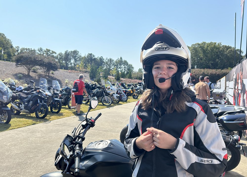 shot of the teenage girl rider smiling in front of motorcycles at the festival