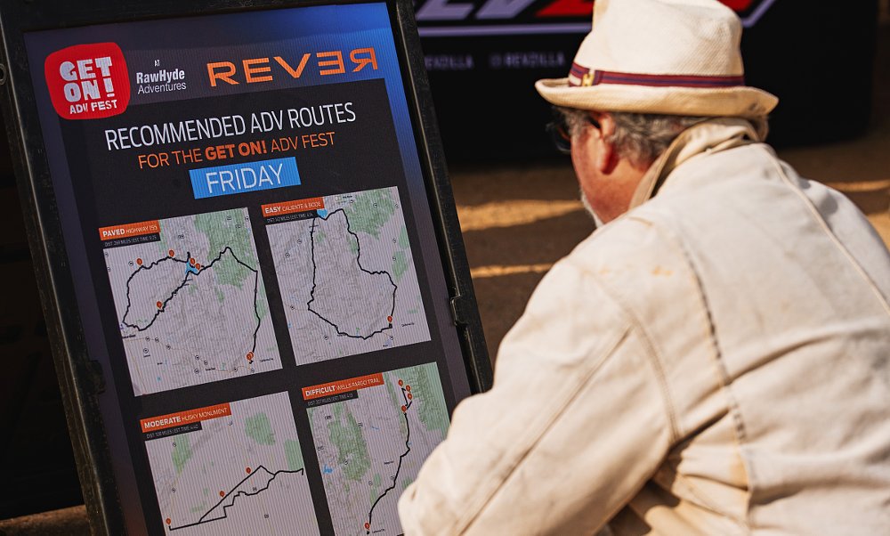a man examines a poster listing recommended riding routes at a Get On! Adventure Fest rally