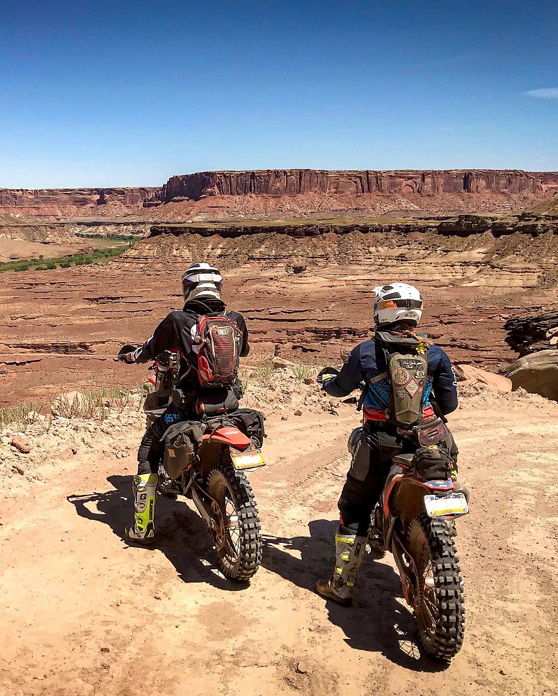 two motorcyclists on off-road bikes overlooking a western red rock canyon