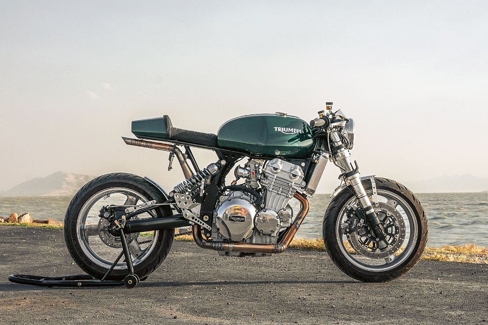 a green Triumph cafe racer with a silver three-cylinder engine