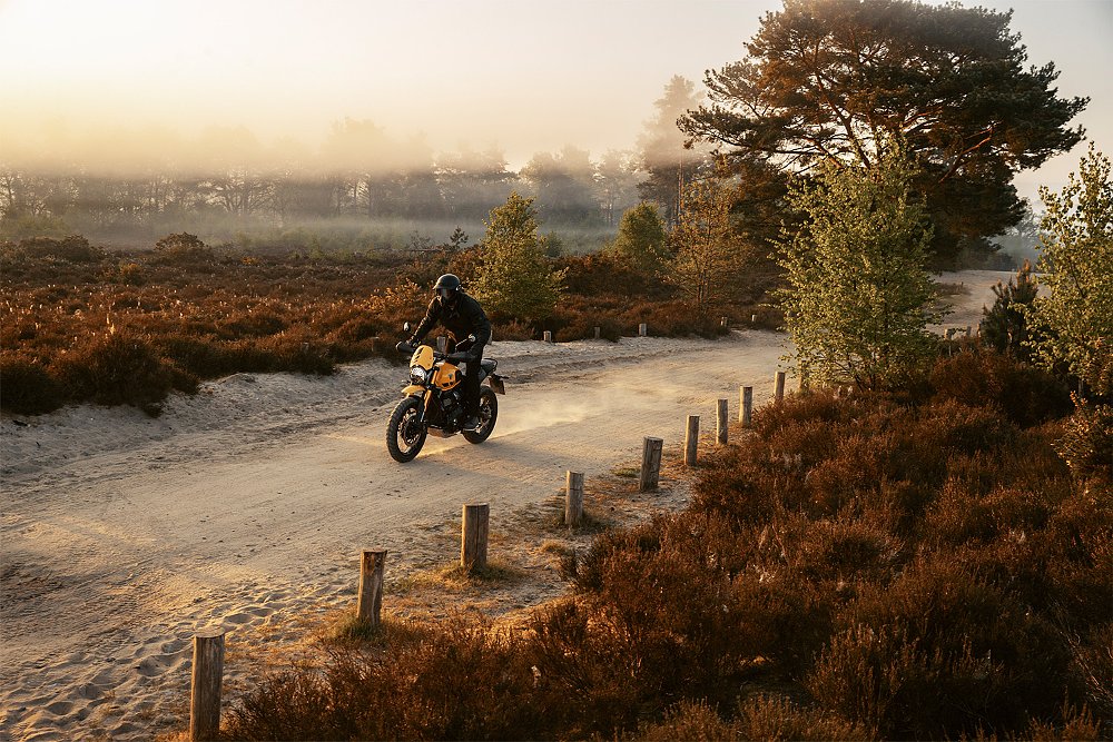 A Scrambler 400 XC rider trundles down a dirt road.