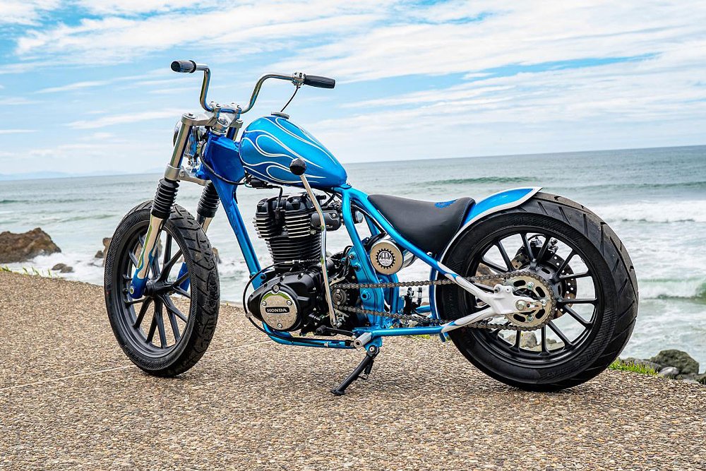blue bobber-style Honda GB350S parked on a beach