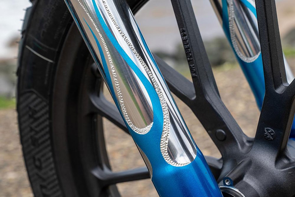 close view of blue paint flames and pebbled metalwork on the fork leg