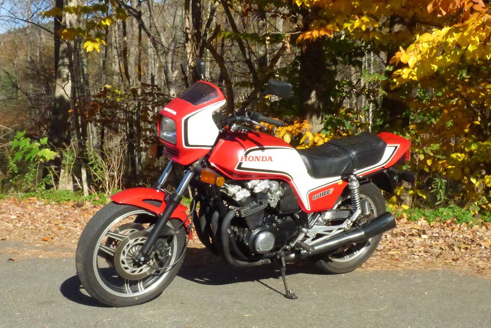 red and white 1983 Honda CB1100F parked under trees in fall colors